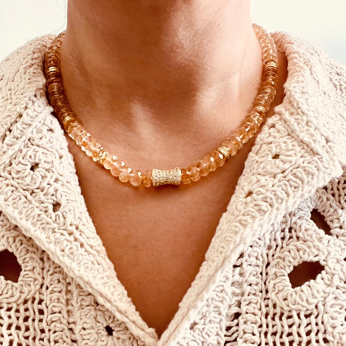 Citrine beaded necklace with citrine amber-colored beads and a central textured white bead, paired with a cream crochet cardigan.