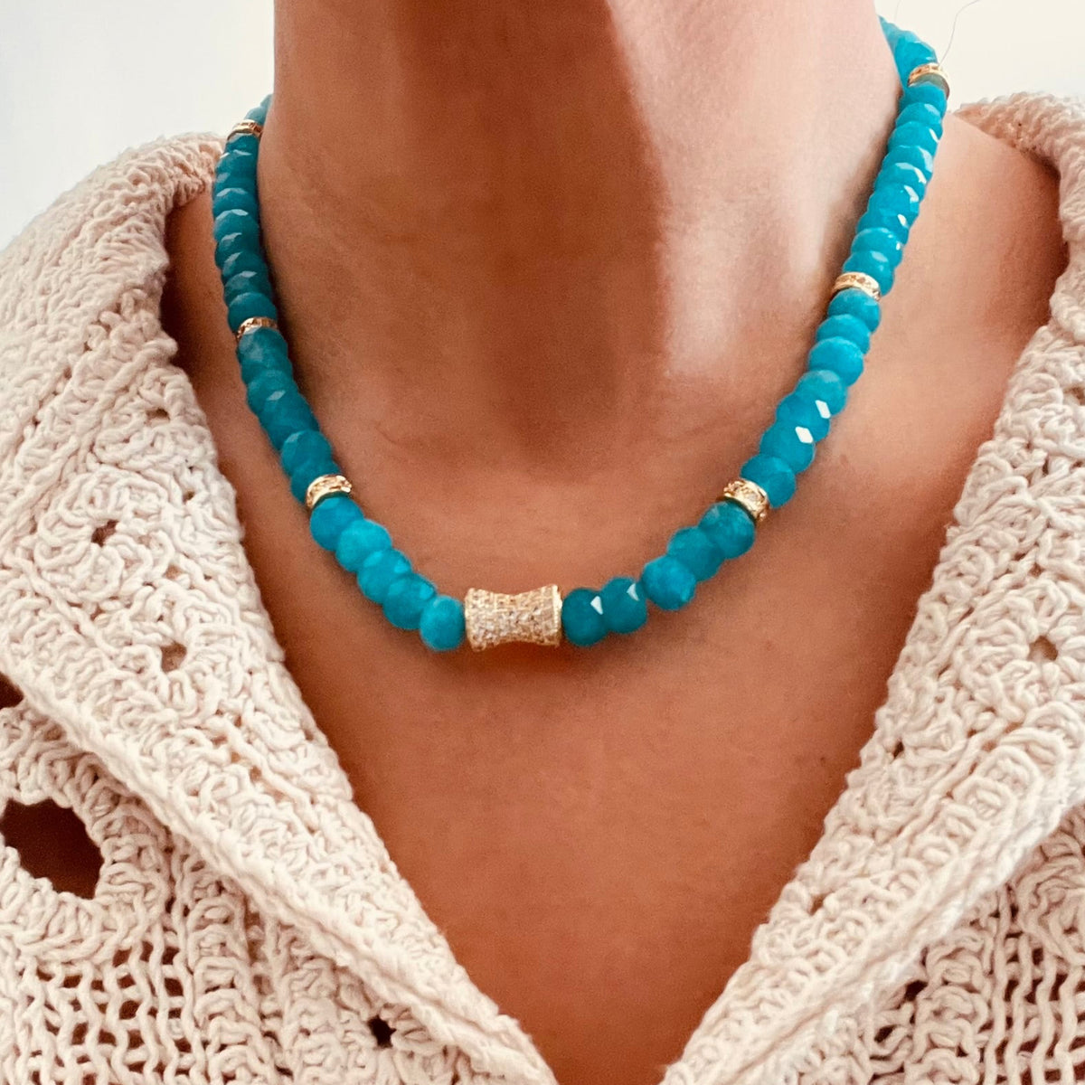 Natural Turquoise Amazonite beaded necklace with a textured gold center accent, paired with a cream-colored crochet cardigan.