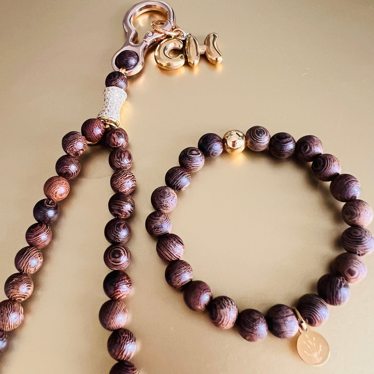 A set of Sandalwood beaded jewelry, including a long prayer bead Wristlet with a gold-toned lobster clasp and a matching beaded bracelet with a small round gold charm.
